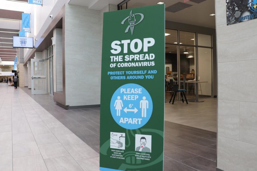 A sign instructing students to be mindful of the spread of COVID-19 stands in the hallway. Students began the first three days of school by social distancing and keeping face masks on throughout the entire school day.