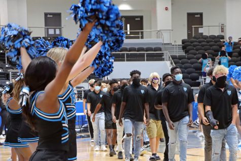 Cheerleaders wave as the football team walks down the arena court. Football played their first game last Thursday against Frisco Heritage but lost. "We haven't been practicing that long," junior and wide receiver Ryan Threat said. "But I feel that our team chemistry is getting better everyday."