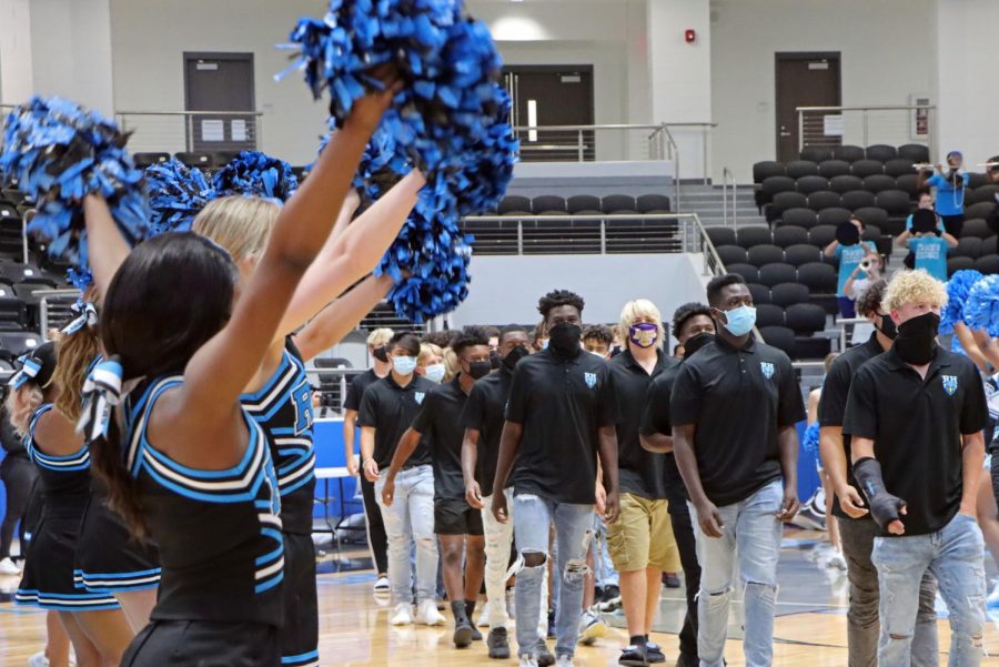 Cheerleaders wave as the football team walks down the arena court. Football played their first game last Thursday against Frisco Heritage but lost. "We haven't been practicing that long," junior and wide receiver Ryan Threat said. "But I feel that our team chemistry is getting better everyday."