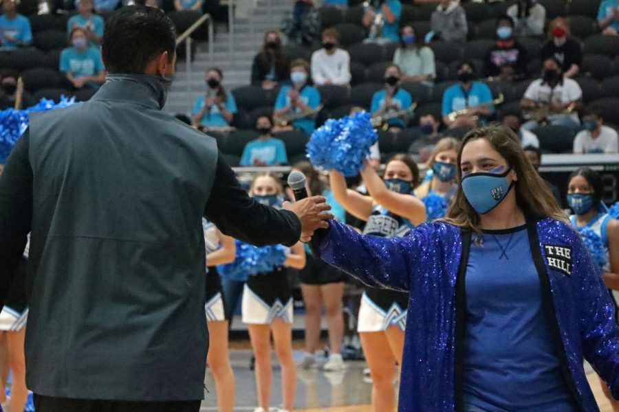 Theatre teacher and pep rally host Sariea Haney hands the microphone off to football coach Mark Humble. Administration had to make a last minute change of who could attend the rally due to positive COVID-19 cases. The upcoming Friday Oct. 2 football game has been canceled due to additional cases.