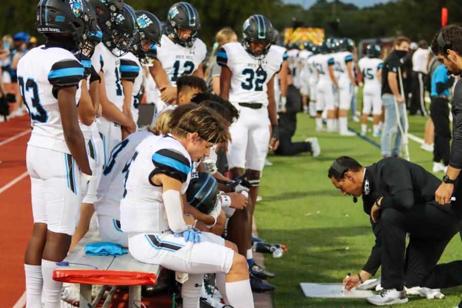 The team listens to football coach Mark Humble while he works out a play. The Blue Hawks played their first game away against the Coyotes. The Friday Oct. 9 game has been moved to Saturday Oct. 10. 