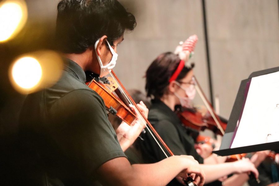 Violin players Prasanna Padmanathan and Hailey Percil Duncan perform at the orchestra concert Dec. 10. The group played holiday songs for family and students. The orchestra was able to play indoors while sporting masks and holiday gear. 