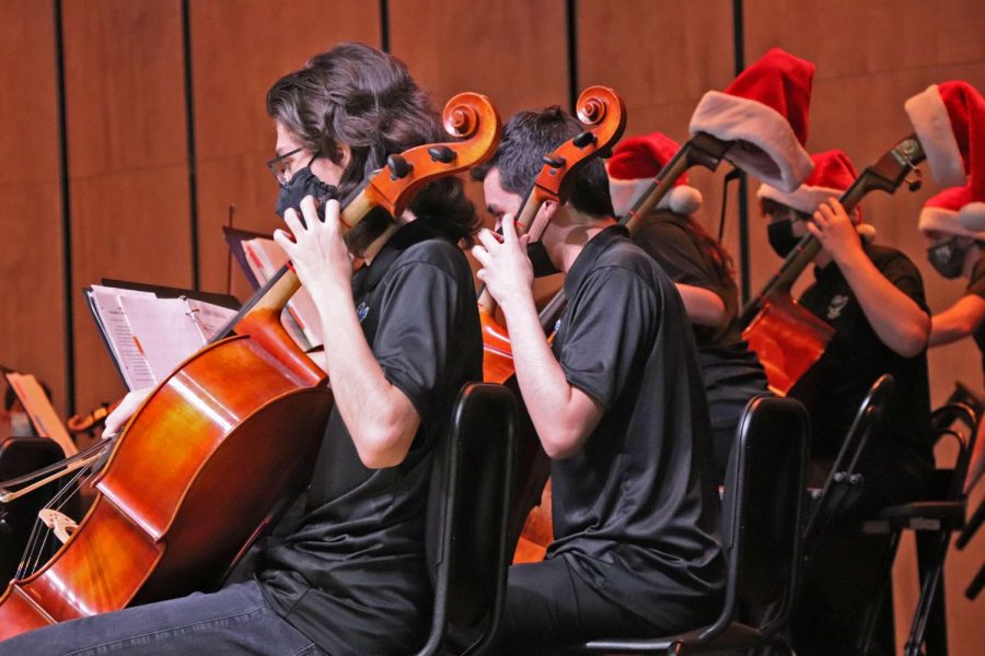 (Left to right) Orchestra members Erick Plats, Gavin Dalton, Daniella Mijares-Crespo, and Anthony Frances play with Christmas-decorated instruments at the holiday concert. The group used Santa hats and Christmas decor around the stage to spread holiday cheer. All who attended and performed in the showcase were required to wear a mask.