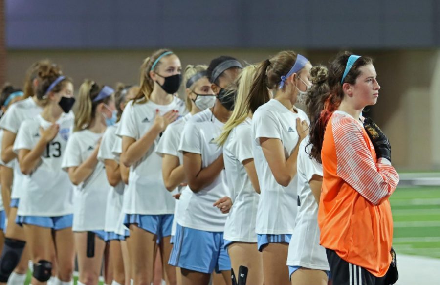 Varsity girls soccer stands on the sidelines at Children's Health Stadium for the national anthem. Prosper High School's team stood directly across the field before the start of the game.  The team lost to Prosper with a final score of 0-2.