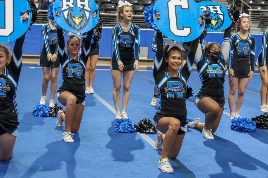 Cheer holds up signs at the spring Meet the Blue Hawks event. Other clubs such as color guard and the Rockettes performed, as well. The event took place in the high school arena and introduced spring athletics.