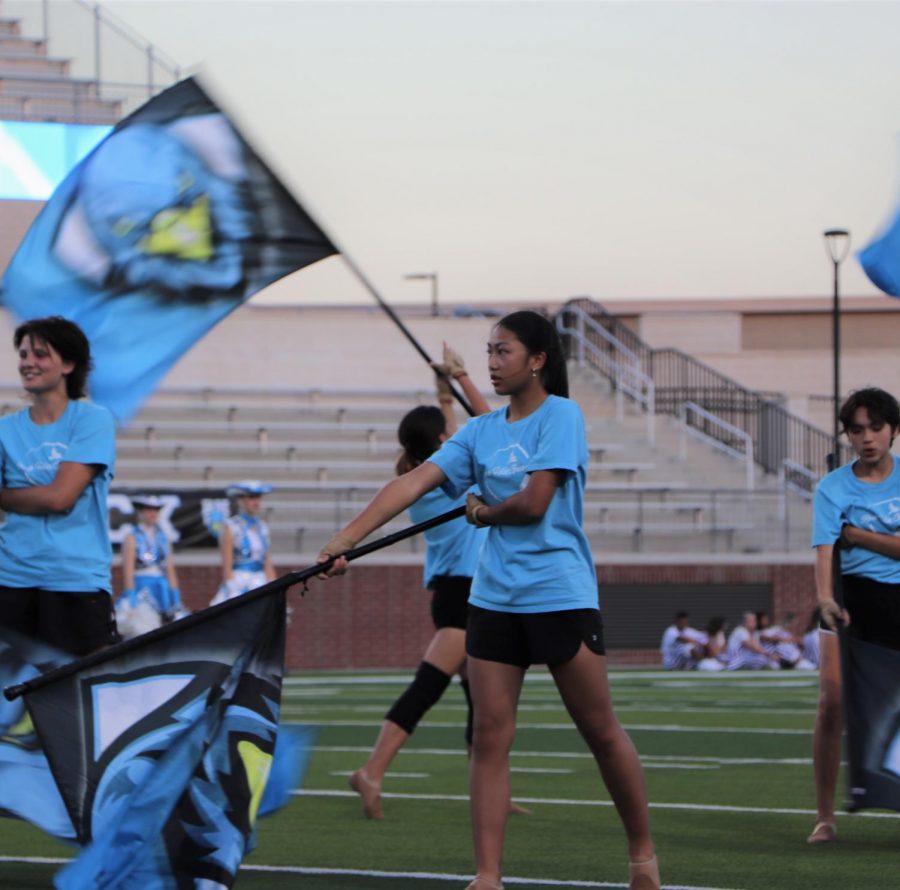 Color Guard member, Kayla Tran, performs choreography with flag.