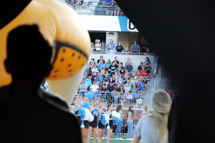 Audience cheers on as varsity tennis players walk through the inflatable.