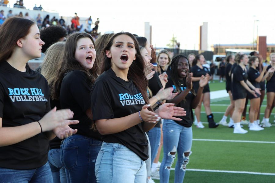 Girls Volleyball (Included in the picture: Grace Cross, Emma Santoni, and Lauren Northcutt) applaud while watching hype video.