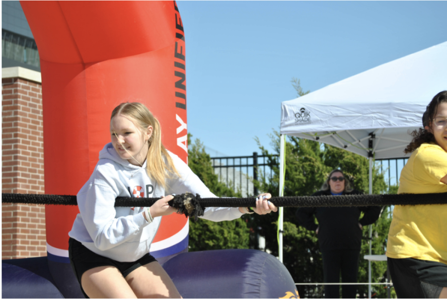 Pictured at the tail end of their first pull are juniors and Hope Squad members Grace Quin (right) and Erin Lewis (left). "My favorite part of the day," Doyle said, "I think, was just getting to see the community impact and how everybody was just so happy to be there and so positive around it." Hope Squad had frequent assistance in their pulls from other teams as they did not have a ten-man team.