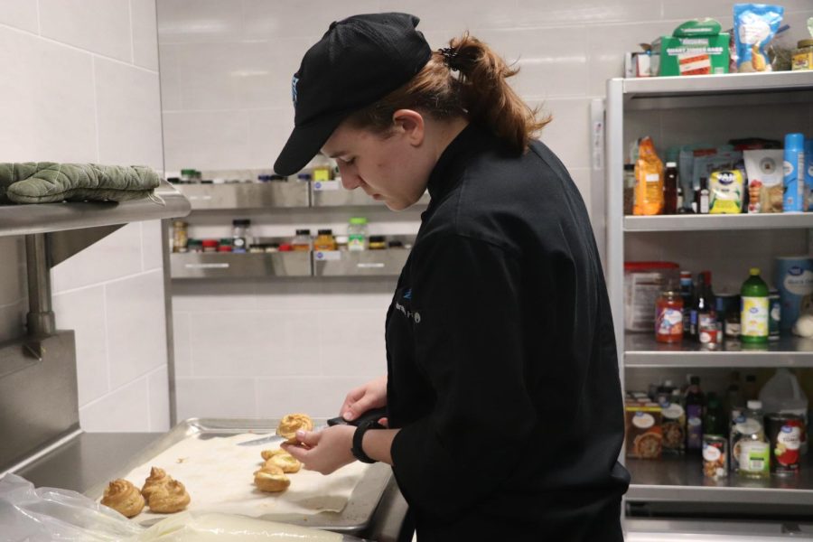 Senior Samantha Harrington cuts open Italian cream puffs to fill them with sweet cream during her Practicum Culinary class. “I love Italian food,” Harrington said. “I worked at an Italian restaurant over the summer and gained all the knowledge needed for [the Italian menu].” Hilltop Cafe is a student run cafeteria offering cuisines from around the world as well as seasonal menus.