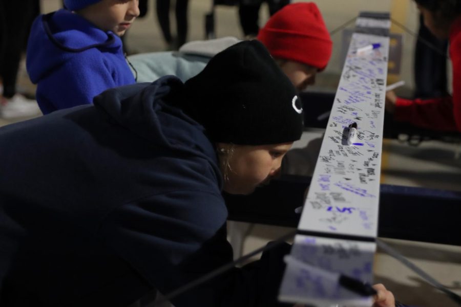 A student looks the beam over to find a place for her signature.