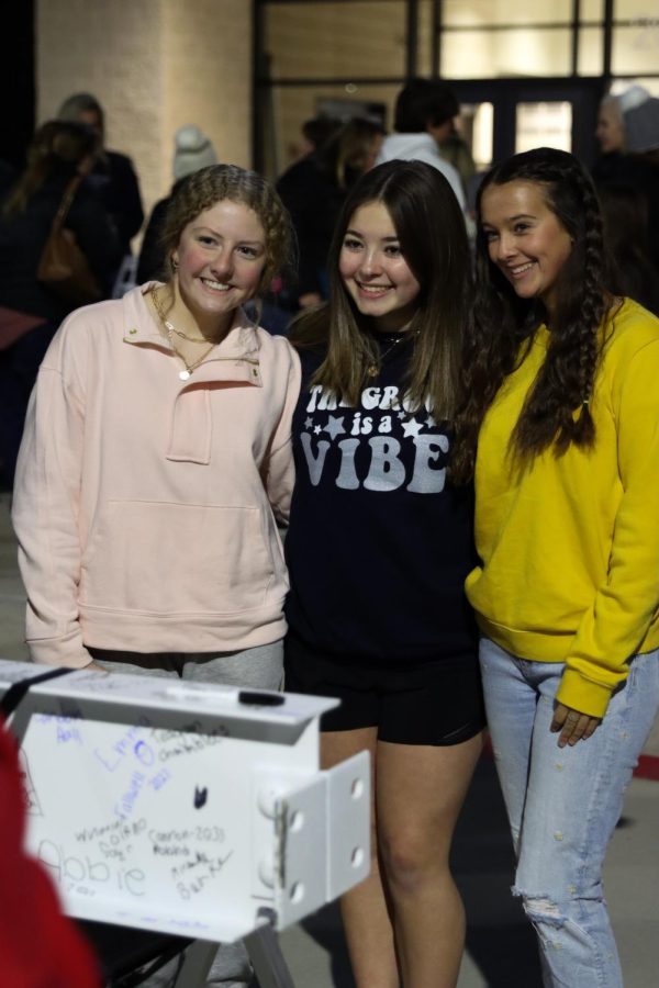 Three students stand in a line while taking a photo. One can be seen wearing signature WGHS apparel. 