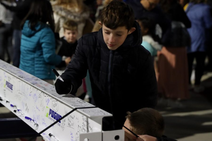 With a smile on his face, PISD student signs his name on the beam, making a permanent impact.