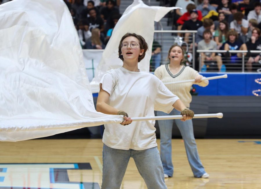 As a part of the Color Guard, junior Bowie Savor waves her white flag in the air along with the routine.