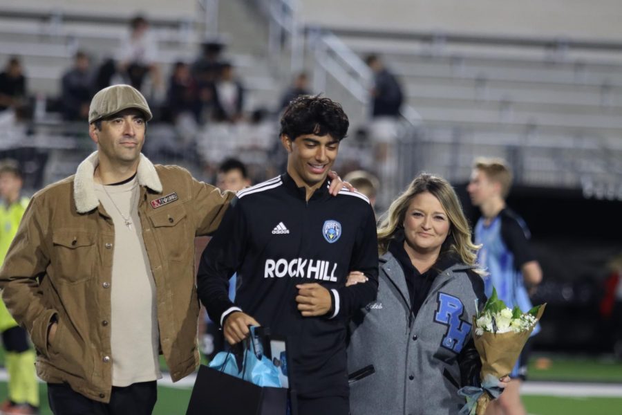 Senior forward Caleb Zavala walks down the field with his parents as part of recognition for senior night. Zavala went on to score a goal for the Blue Hawks during the second quarter. 