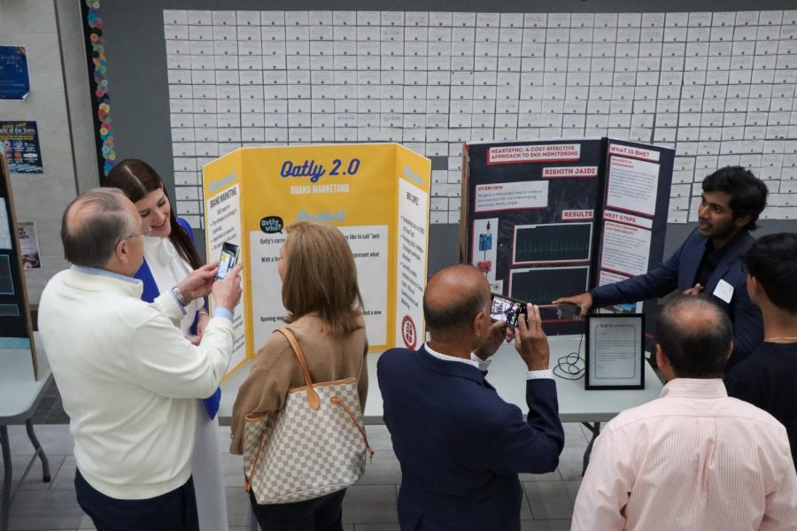 Two members of PCIS showcase their work while the audience takes pictures and videos of their research. "First we learned about networking, we looked into Linkedin specifically, and interviewed potential mentors to learn about their job and whether they would be suitable for us," senior PCIS member Isha Thirupathy said. "Then we got a mentor and met with them once a month to shadow or learn about their job or work on our final project." 