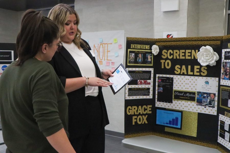 Portraying the Screen To Sales poster, senior Grace Fox explains her research. 