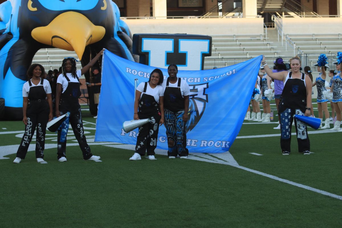 Yell leaders present their school flag onto the field. 