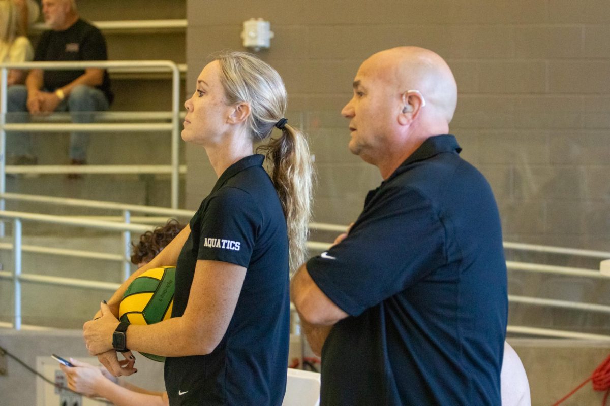 Lauren Steinhouse, Head Coach, and District dive coach, -----, watch intently as their athletes play hard in the pool. Coach Steinhaus said she became a coach due to be able to teach valuable life lessons such as perseverance, hard work, consistency, and the ability to dig deep and face challenges with  a positive attitude.