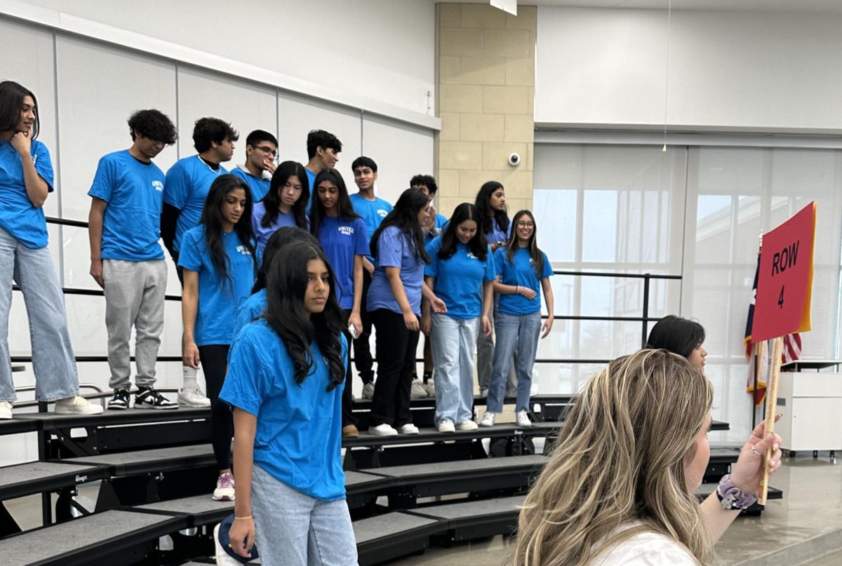 A group of students begin to step off of stands after taking a club group picture for the yearbook.