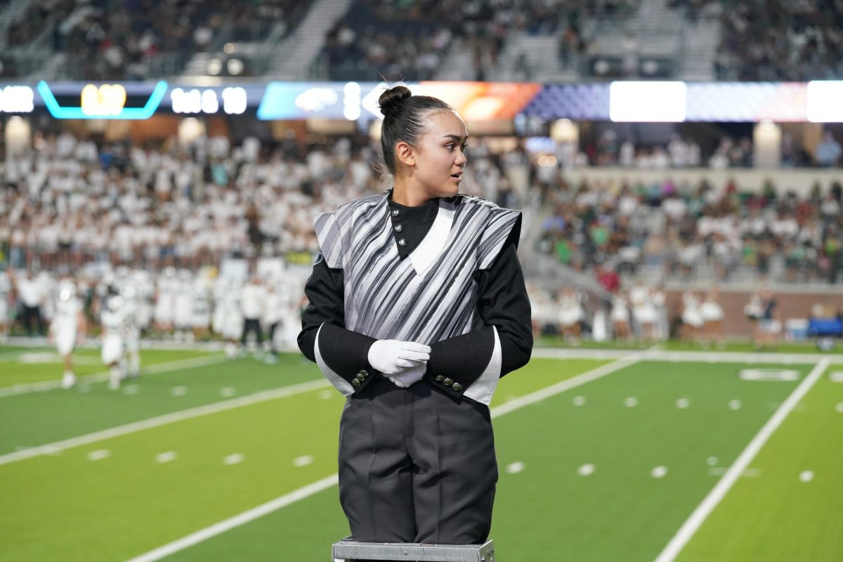 Senior Madi Kang stands on a podium at a football game. "Being a drum major has definitely helped me," Kang said. "It's helped me put myself out there, both socially and with my leadership."