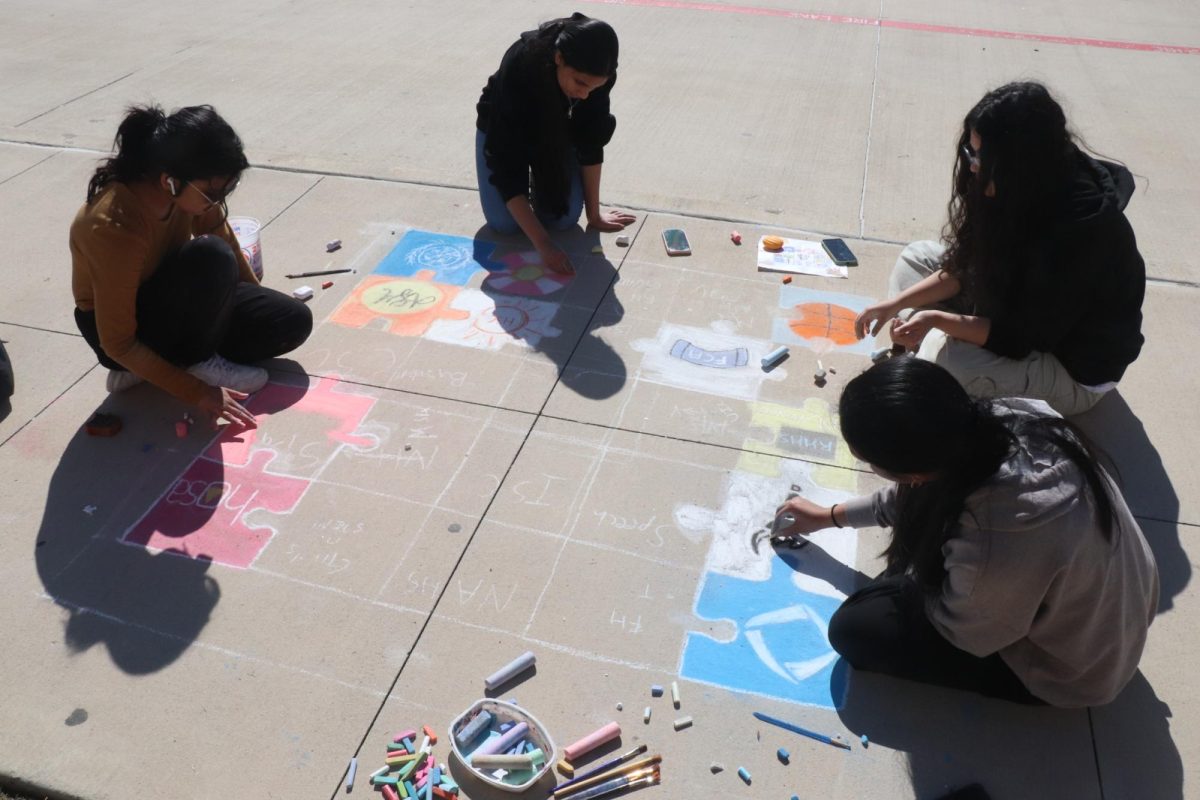 Sketching on a full puzzle for their chalk mural, the students seem to be drawing on behalf of all clubs and organizations for this school. 