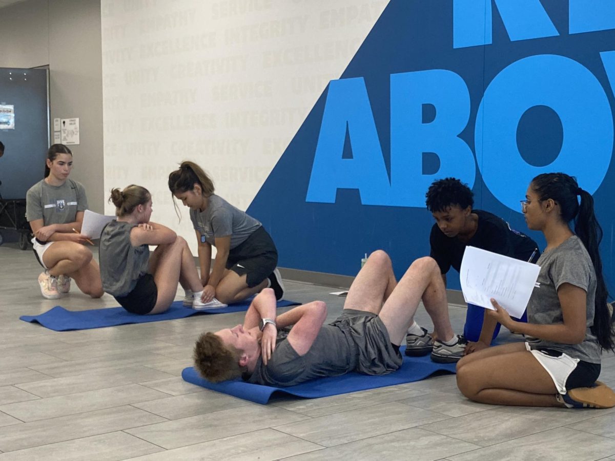 JROTC cadets assist each other with curl-ups during physical training.  “Going out and competing and winning, especially, brings so much confidence to everyone on the team, and we feel really close, as a family,” senior cadet Soumika Annam said.