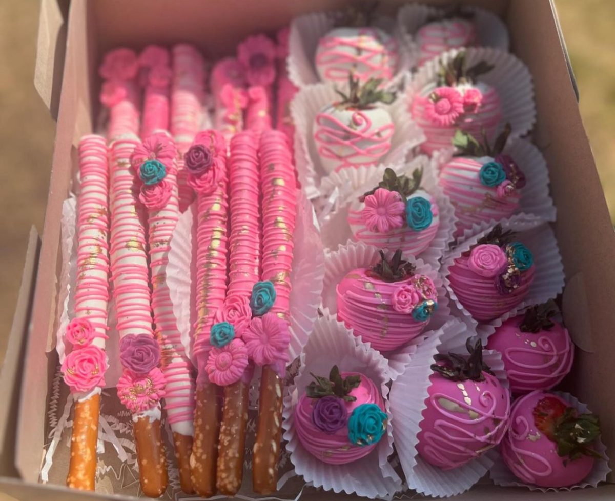 An order of pink dipped strawberries and pretzels decorated with colorful florals.