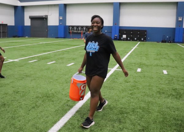 In the athletic building, senior Michaela Wilson carries a bucket of ice water for the football players to have a drink. “Tasks such as these may seem mundane, but a simple detail such as keeping the [coolers] full helps the athletes perform at their best,” Wilson said.