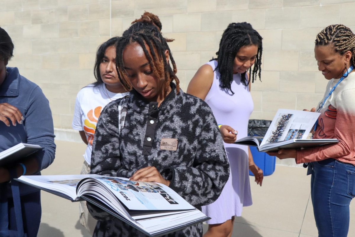 Seniors wait outside for the food trucks to arrive while setting up for for the party. They look through their long awaited yearbooks in the meantime.