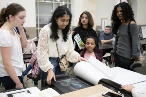 Saanvi Kanti, Clara Schultz, and Marley Edgely looking at Kanti's artwork before interviews begin.