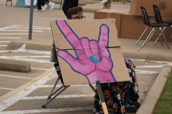 A cardboard sign depicting a hand sign in ASL.