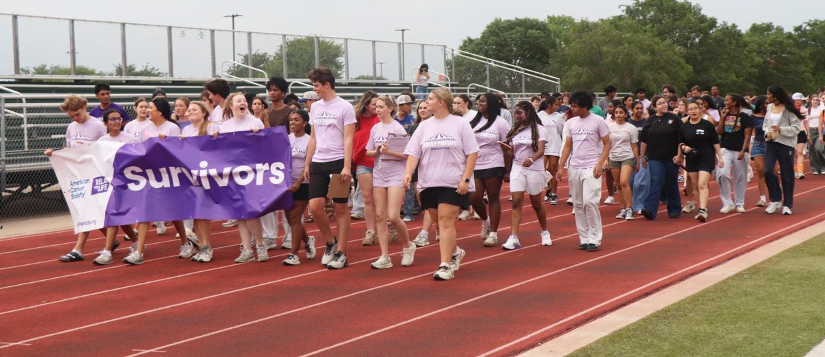 Students from different clubs walking around the track at Prosper High School. 